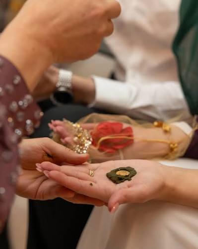 Hände beim Henna-Abend, Henna und eine Goldmünze liegen in der offenen Handfläche